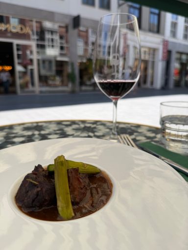 Gastronomisch gerecht met een glas rode wijn op het terras van restaurant DE WIJNCLUB in Breda, gefotografeerd voor social media content.